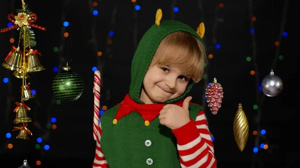 Adolescente criança menina no Natal elfo Papai Noel ajudante traje mostrando polegares para cima no fundo preto — Fotografia de Stock