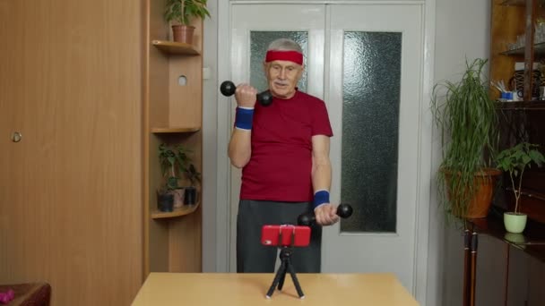Seniorzy Dojrzały mężczyzna oglądanie online odległość ćwiczenia z hantlami na telefon komórkowy — Wideo stockowe