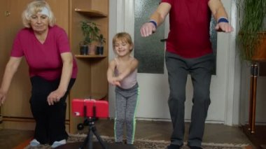 Büyükanne büyükbaba ve kız çocuğu evde egzersiz yapıyor, antrenman yapıyor, spor yapıyor.