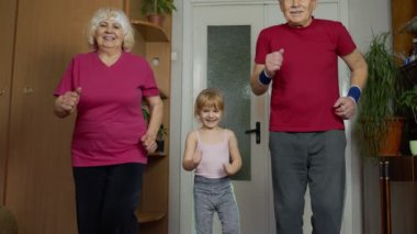 Aktif yaşlı çift büyükanne, büyükbaba ve küçük kız çocuk spor yapıyor.