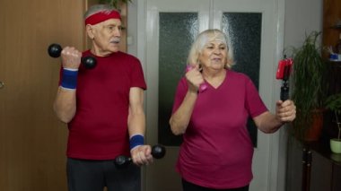 Online antreman izleyen yaşlı çift cep telefonu eğitimi ve dambılı kullanıyor.