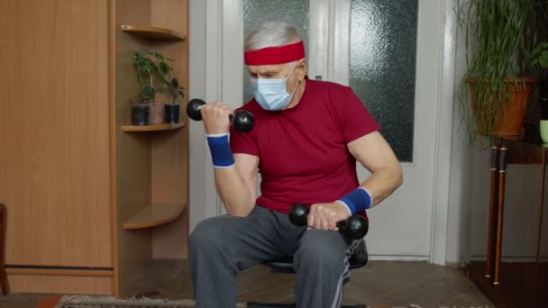 Starszy osoby w podeszłym wieku biały mężczyzna robi hantle podnoszące ciężar ćwiczenia w domu podczas koronawirusu — Wideo stockowe