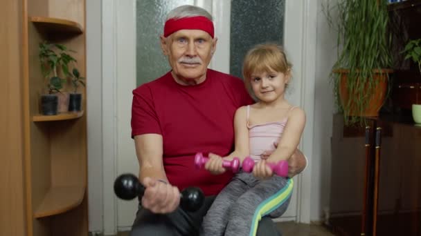 Barn flicka med äldre farfar i sportkläder gör sport träning övningar med hantlar — Stockvideo