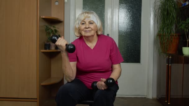 Senior äldre mormor kvinna gör tyngdlyftning träning fitness hantlar utövar hemma — Stockvideo