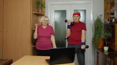 Yaşlı yaşlı çift büyükanne büyükbaba halterlerle egzersiz yapıyor, spor yapıyor.