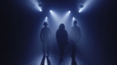Vokalist kız, saksafoncu saksafoncu, kulaklıklı DJ 'in arka ışıklandırılmış siluetleri.