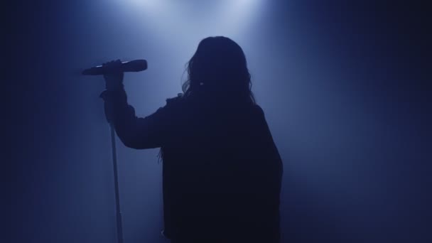 Bakgrundsbelyst siluett av sångerska sångerska flicka stående i mörk nattklubb disco studio och börja sjunga — Stockvideo