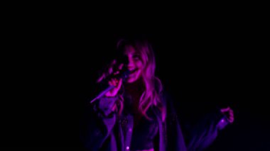 Karanlıktaki şarkıcının canlı performansı, neon ışıklı dans eden güzel kız, şarkı söyleyen.