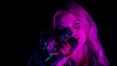 Karanlıktaki şarkıcının canlı performansı, neon ışıklı dans eden güzel kız, şarkı söyleyen.