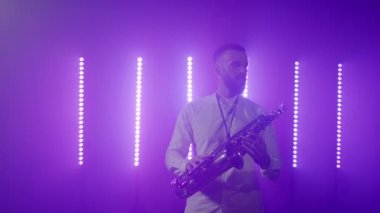 Saksafoncunun canlı performansı, saksafoncu adam, konser müzisyeninin sahnesinde ışıklarla dans ediyor.
