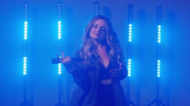 Kot ceketli duygusal şarkıcının canlı performansı, dansçı kız sahnede şarkı söylüyor.