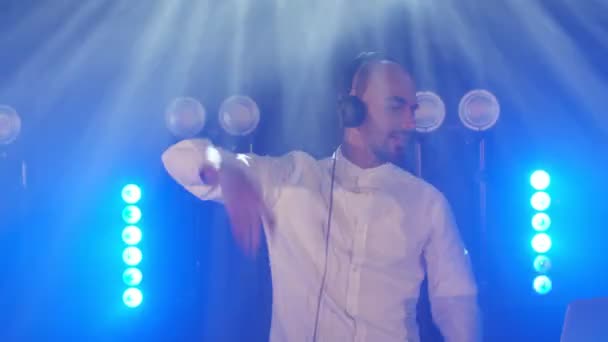 Canlı DJ performansı, kulaklıklı enerjik kel bir adam, parti konser sahnesinde dans ediyor. — Stok video