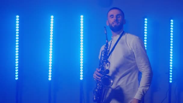 Szaxofonos szaxofonos férfi élő előadása, aki a koncert zenészszínpadán táncol fényekkel