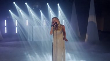 Duygusal şarkıcının canlı performansı, dansçı kız sahnede dumanla şarkı söylüyor.