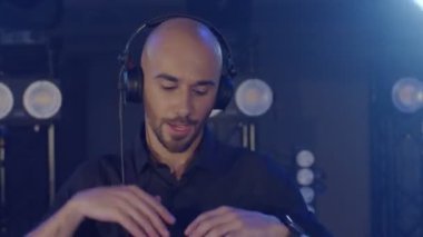 Canlı DJ performansı, kulaklıklı enerjik kel bir adam, parti konser sahnesinde dans ediyor.