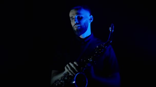 Actuación en vivo del saxofonista con saxofón, bailando en el escenario del concierto con luces de neón azul — Vídeo de stock