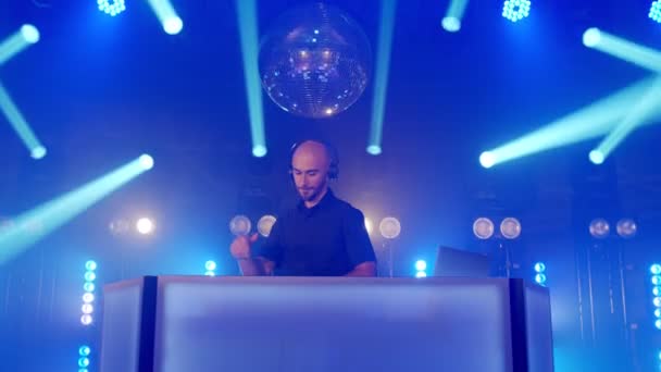 Live-DJ-Auftritt eines energischen Glatzkopfhörers, der auf der Bühne eines Party-Konzerts tanzt — Stockvideo