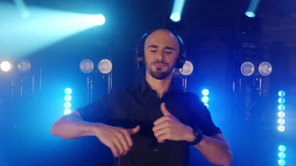 Canlı DJ performansı, kulaklıklı enerjik kel bir adam, parti konser sahnesinde dans ediyor. — Stok video