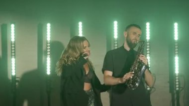 Şarkıcı kadın müzik grubu, saksafoncu saksafoncu adam müzik çalıyor, sahnede şarkı söylüyor.