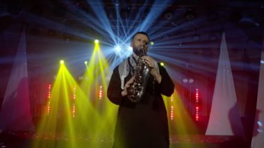 Saksafoncunun canlı performansı, saksafoncu adam, konser müzisyeninin sahnesinde ışıklarla dans ediyor.