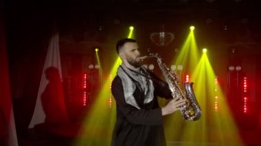 Saksafoncunun canlı performansı, saksafoncu adam, konser müzisyeninin sahnesinde ışıklarla dans ediyor.