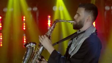 Saksafoncunun canlı performansı, saksafoncu adam, konser müzisyeninin sahnesinde ışıklarla dans ediyor.