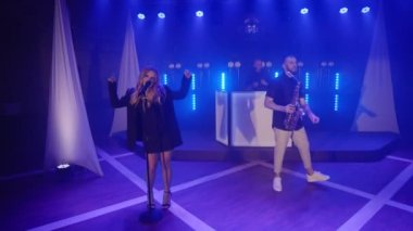 Şarkıcı kadın müzik grubu, saksafoncu, DJ şarkı söylüyor, sahnede şarkı söylüyor.