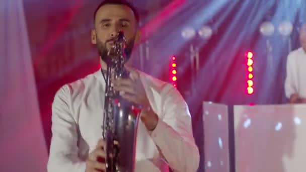 Live performance of saxophonist man with saxophone, dancing on concert musician stage with DJ — Stock Video