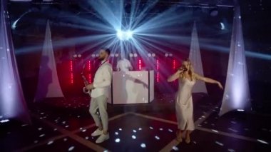 Şarkıcı kadın müzik grubu, saksafoncu, DJ şarkı söylüyor, sahnede şarkı söylüyor.
