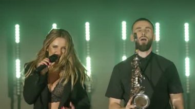 Şarkıcı kadın müzik grubu, saksafoncu saksafoncu adam müzik çalıyor, sahnede şarkı söylüyor.