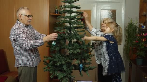 Little cute girl dziecko z dziadków starszych rodziny dekorowanie sztuczne choinki w domu — Wideo stockowe