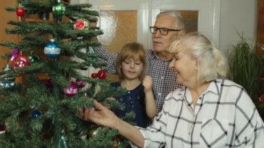 Büyükannesi ve büyükbabası olan çocuklar eski moda evlerinde yapay Noel ağacı süslüyorlar.