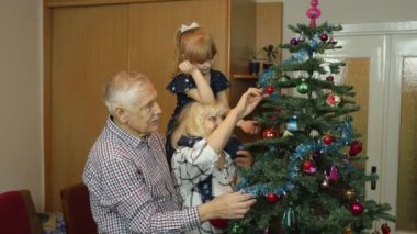 Büyük anne ve büyük babası olan küçük tatlı bir kız. Ailesi evde yapay Noel ağacı süslüyormuş.