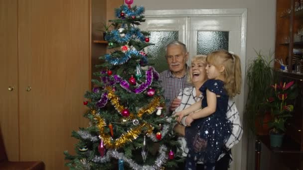 Anak dengan nenek senior dan kakek menghias pohon Natal buatan, lampu karangan bunga — Stok Video