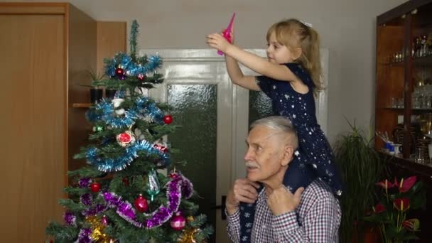 Kindermädchen und älterer Opa schmücken künstlichen Weihnachtsbaum im Altenheim — Stockvideo