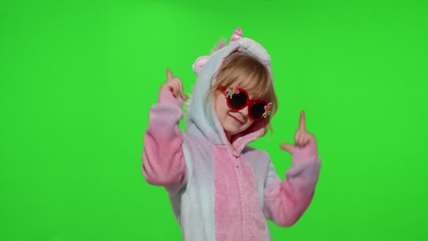 Niña sonriendo, bailando, haciendo gesto de pistola con las manos en pijama de unicornio en croma key — Vídeos de Stock