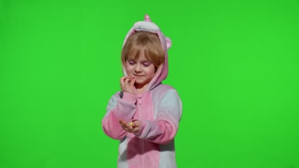 Bambino sorridente, godendo mangiare dolci caramelle dessert in costume unicorno sul tasto chroma — Video Stock