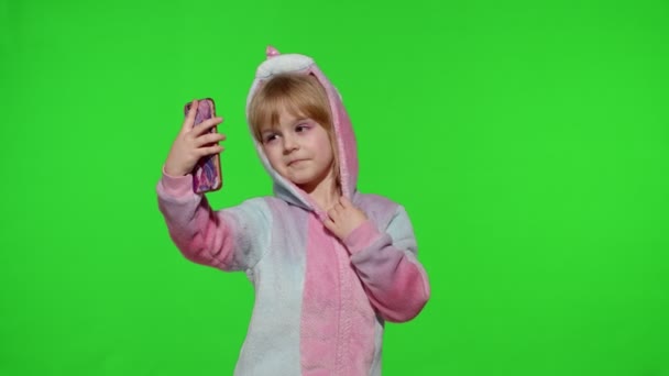 Mädchen im Einhornkostüm im Pyjama mit Smartphone, Kind macht emotional Selfie auf Handy — Stockvideo