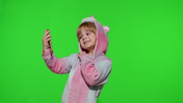 Menina criança em pijama traje unicórnio usando smartphone, criança emocionalmente faz selfie no telefone móvel — Vídeo de Stock