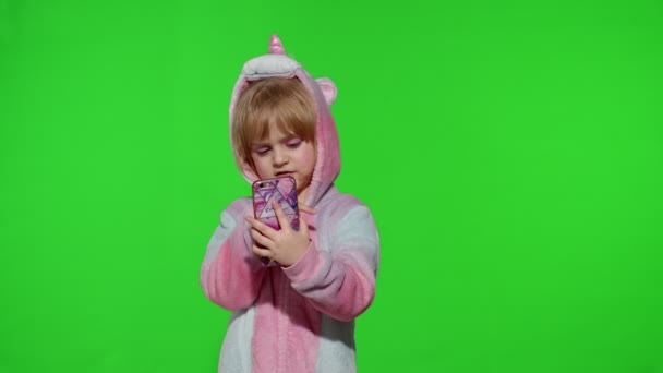 Spännande liten barn flicka i enhörning pyjamas med mobiltelefon, fick reda på stora vinna nyheter — Stockvideo