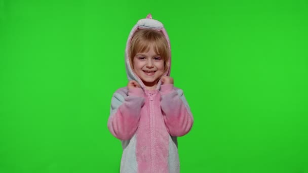 Маленькая блондинка девочка улыбается, танцует, празднует в пижаме единорога костюм на хрома ключ — стоковое видео