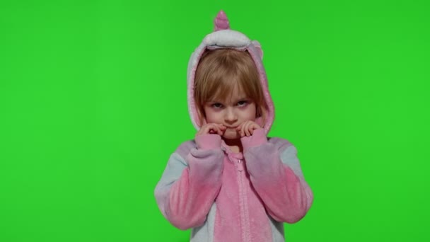 Enfant fille en pyjama licorne faisant des visages drôles stupides, s'amuser autour, montrant la langue sur la clé chromatique — Video