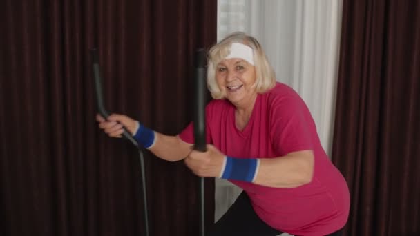 穿着运动服的老年妇女在家里的房间里用轨道器做运动训练和有氧运动 — 图库视频影像