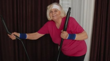 Spor giyim sektöründe etkin, yaşlı, olgun bir kadın. Yörünge turu kullanıyor, evde kardiyo çalışması yapıyor.