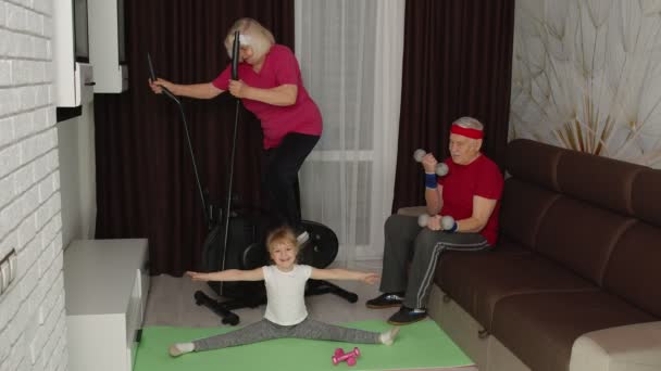 Oudere paar met kleindochter met behulp van orbitrek, het doen van gewicht tillen halters oefeningen thuis — Stockvideo