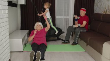 Büyükbaba ve büyükanne orbitrek kullanıyor, ağırlık kaldırma egzersizleri yapıyorlar.