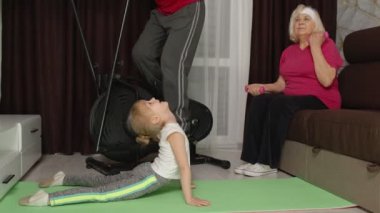 Torunu olan yaşlı bir çift orbitrek kullanıyor, evde ağırlık kaldırma egzersizi yapıyor.