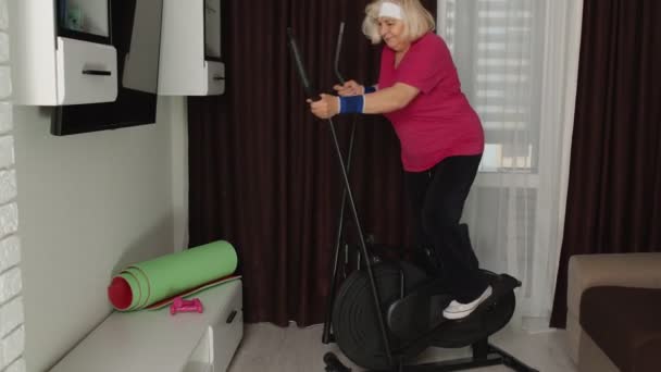 Saludable anciano abuela modelo de ejercicio deportivo entrenamiento en orbitrek en la habitación en casa — Vídeos de Stock