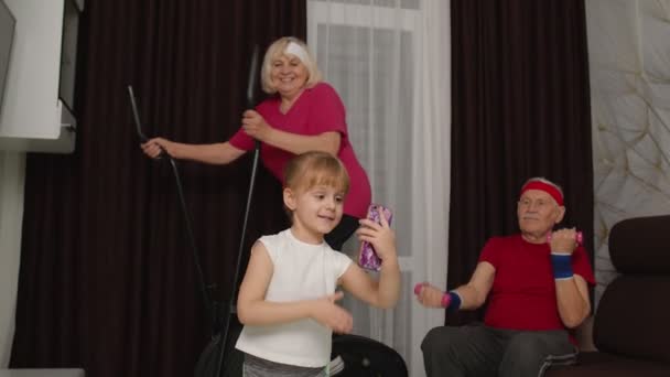 Старша пара використовує орбітрек робить вправи для гантелів, дівчинка робить селфі на мобільному телефоні — стокове відео