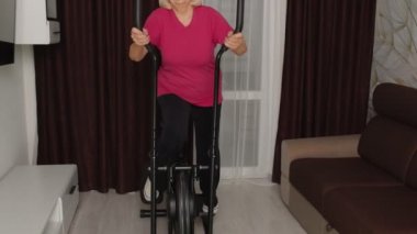 Sağlıklı yaşlı yaşlı büyükanne evde, yörüngede spor egzersizi yapıyor.